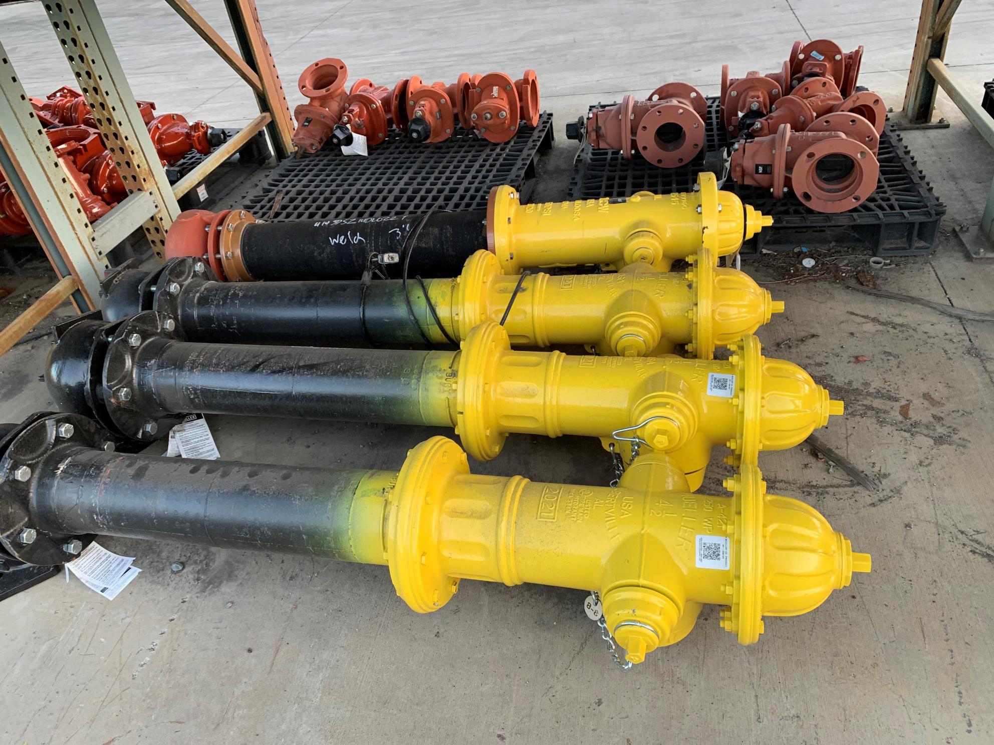 four fire hydrants and spare parts laying on the ground in a row