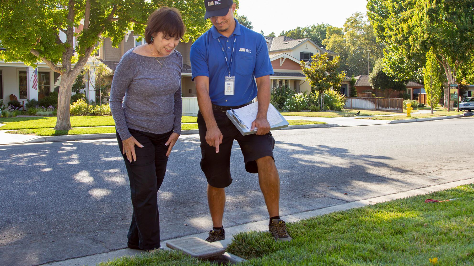 a San Jose Water employee and customer looking at a water meter in the ground