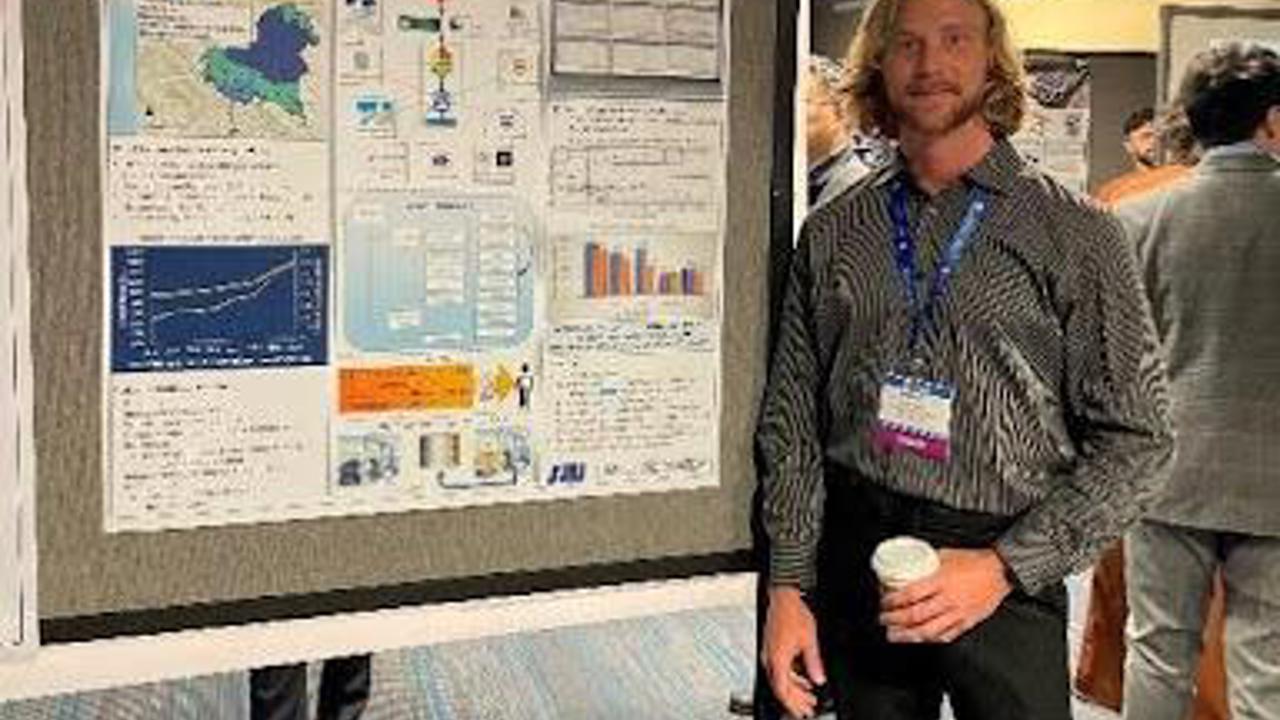 Ethan Smith standing in front of poster