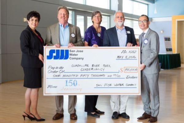 Five smiling executives holding a giant check