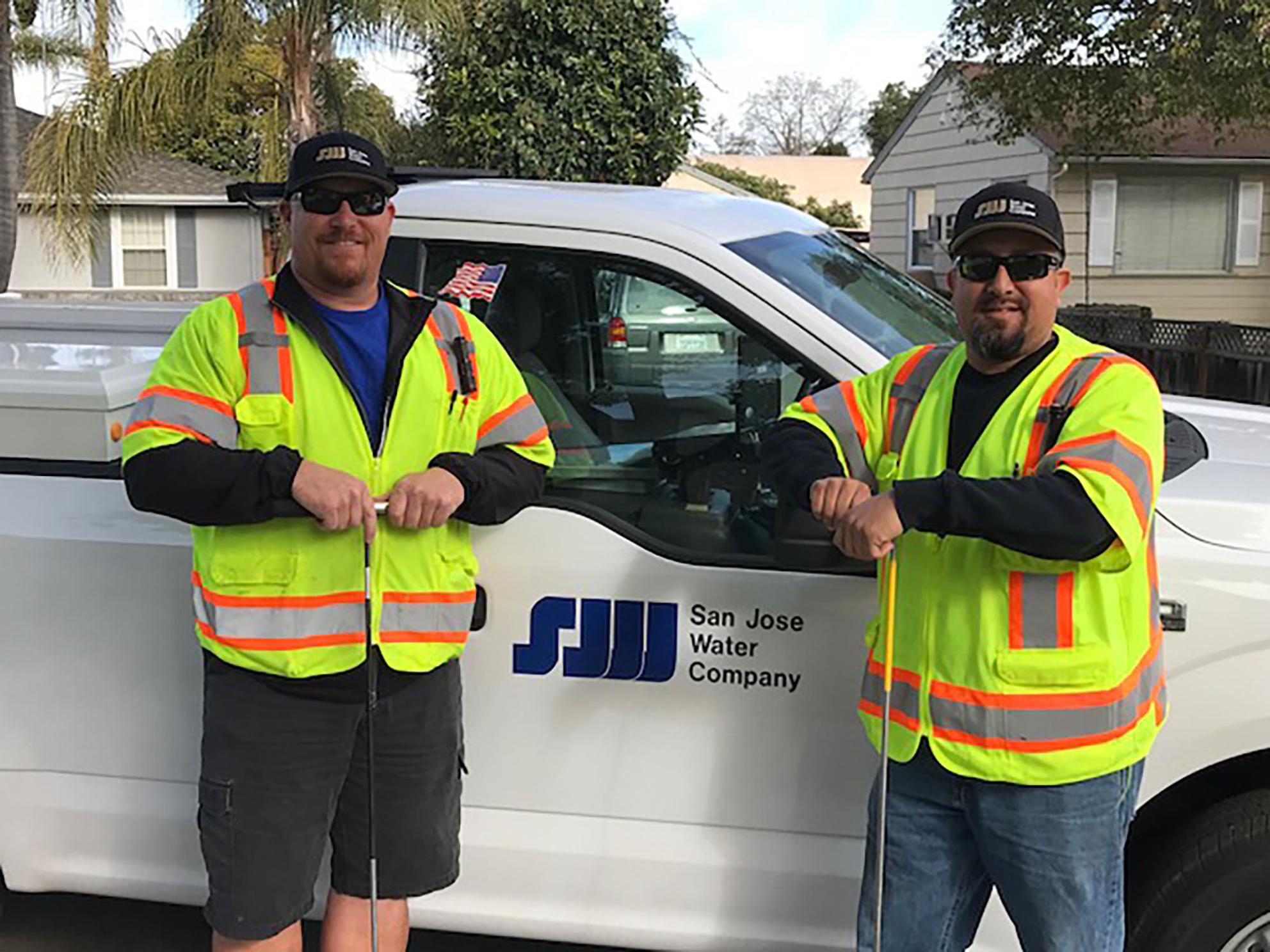 Two SJW employees standing in front of truck