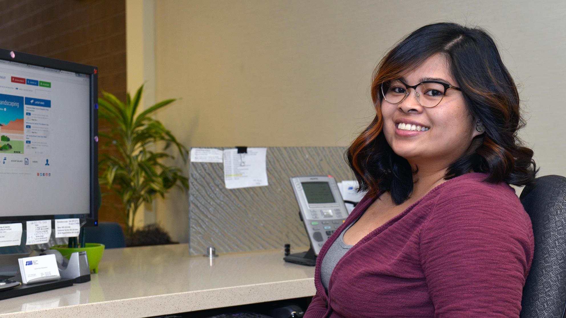 Smiling woman at her desk with a computer in the background