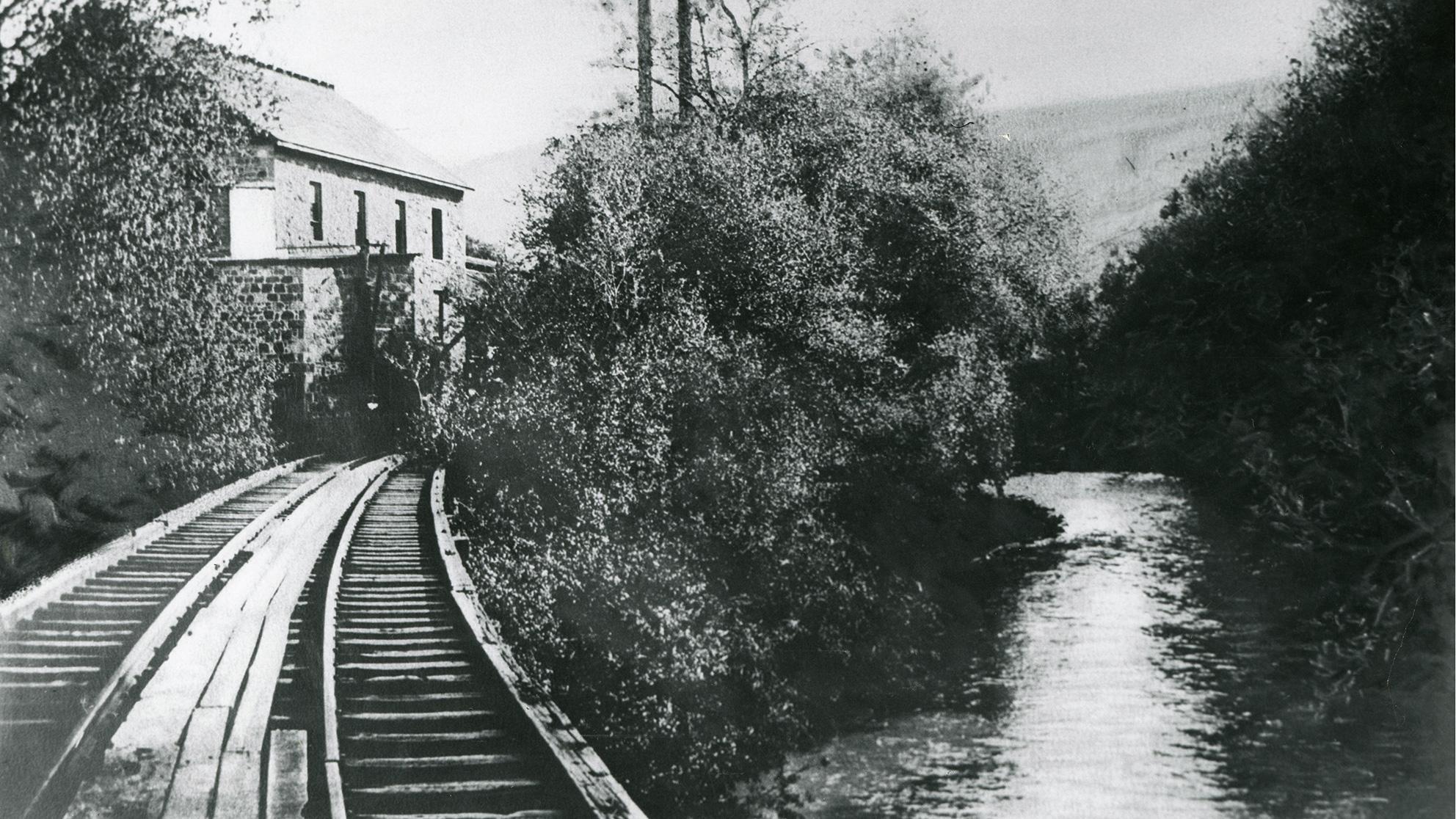 Archival black and white photo of train tracks along a river