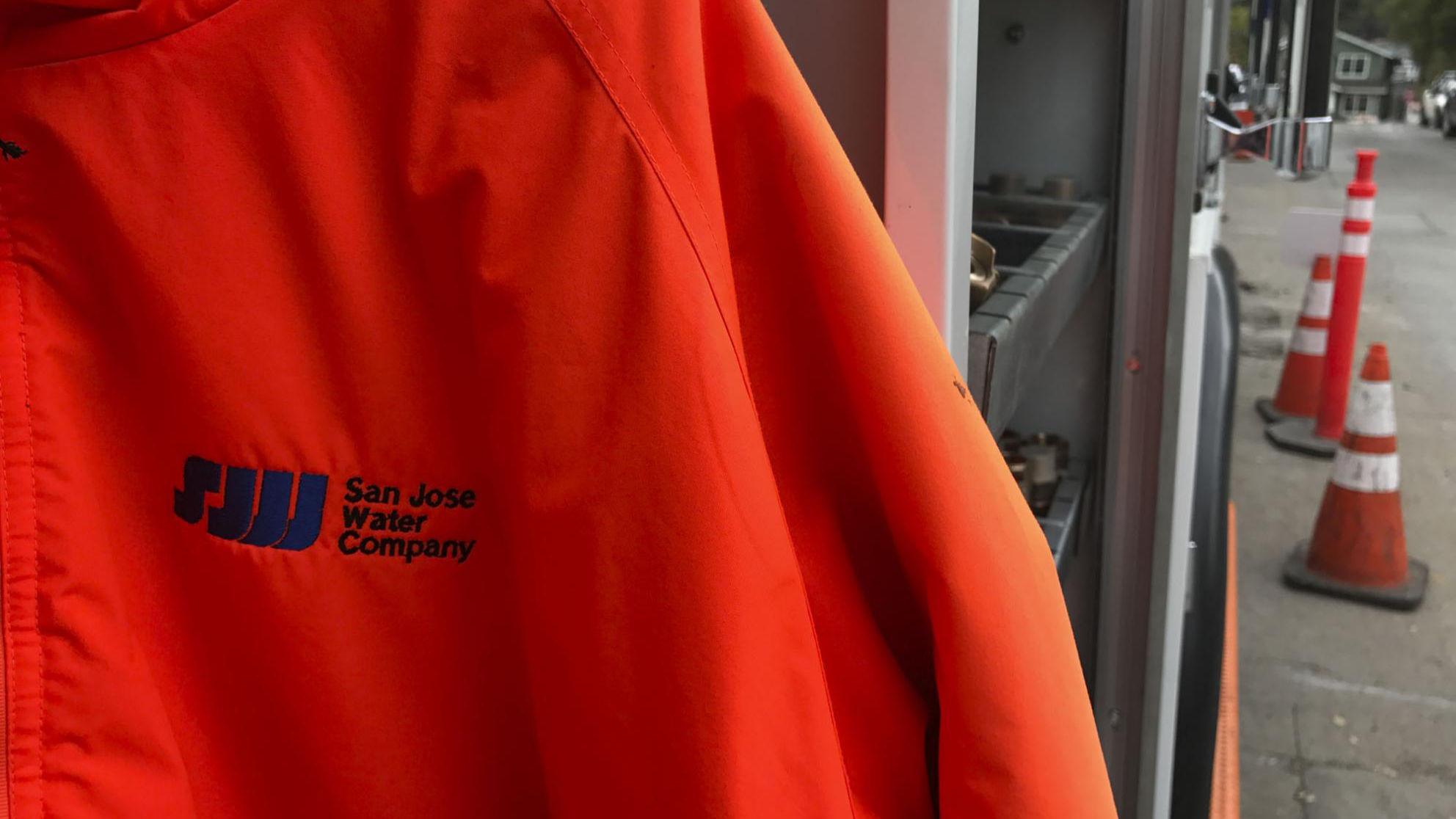 orange-field-jacket.jpg Orange jacket with SJW logo in foreground and pylons in the background