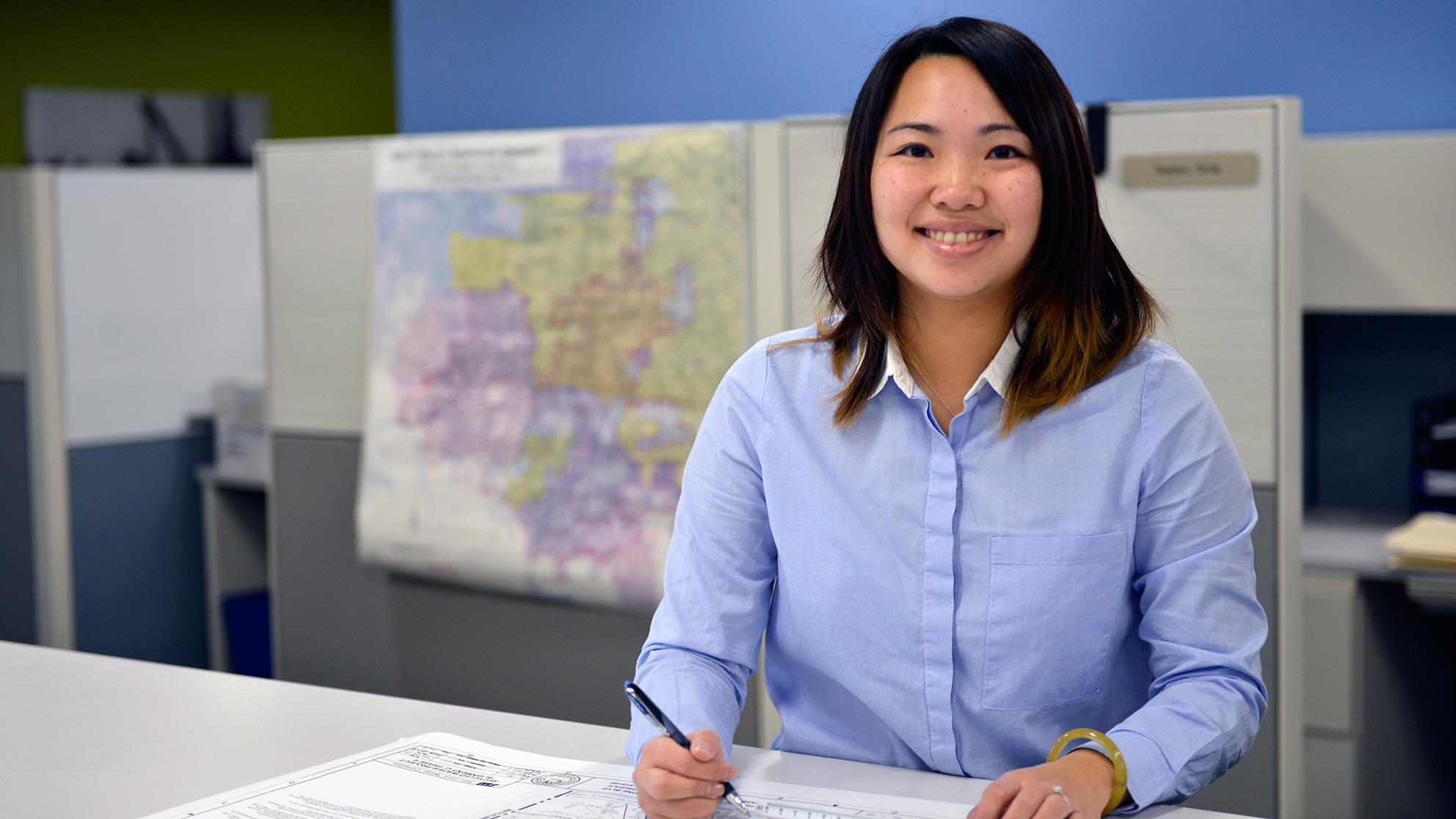 Woman working at a drafting table in front of a map