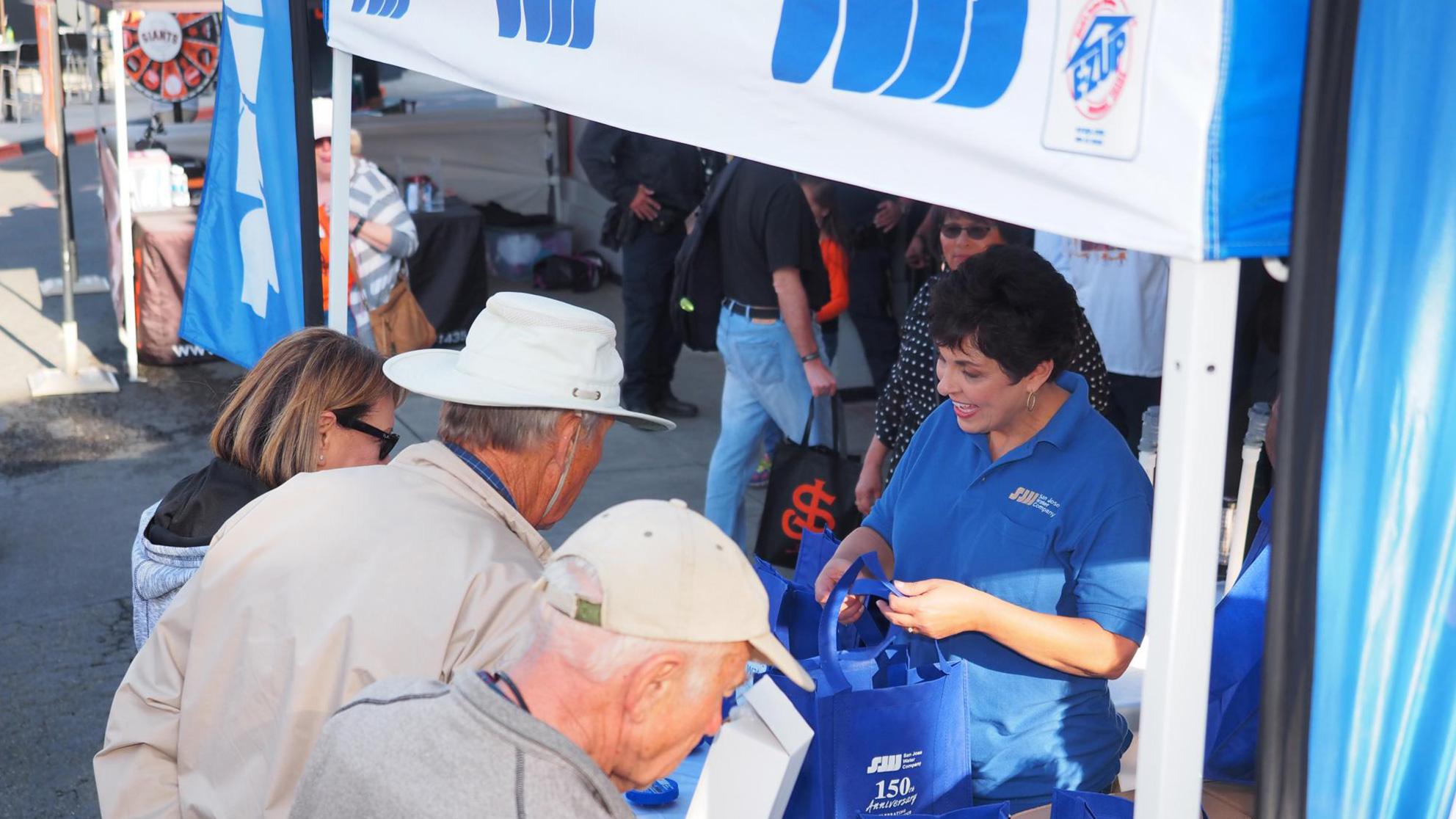 People gather around San Jose Water kiosk at outdoor fair