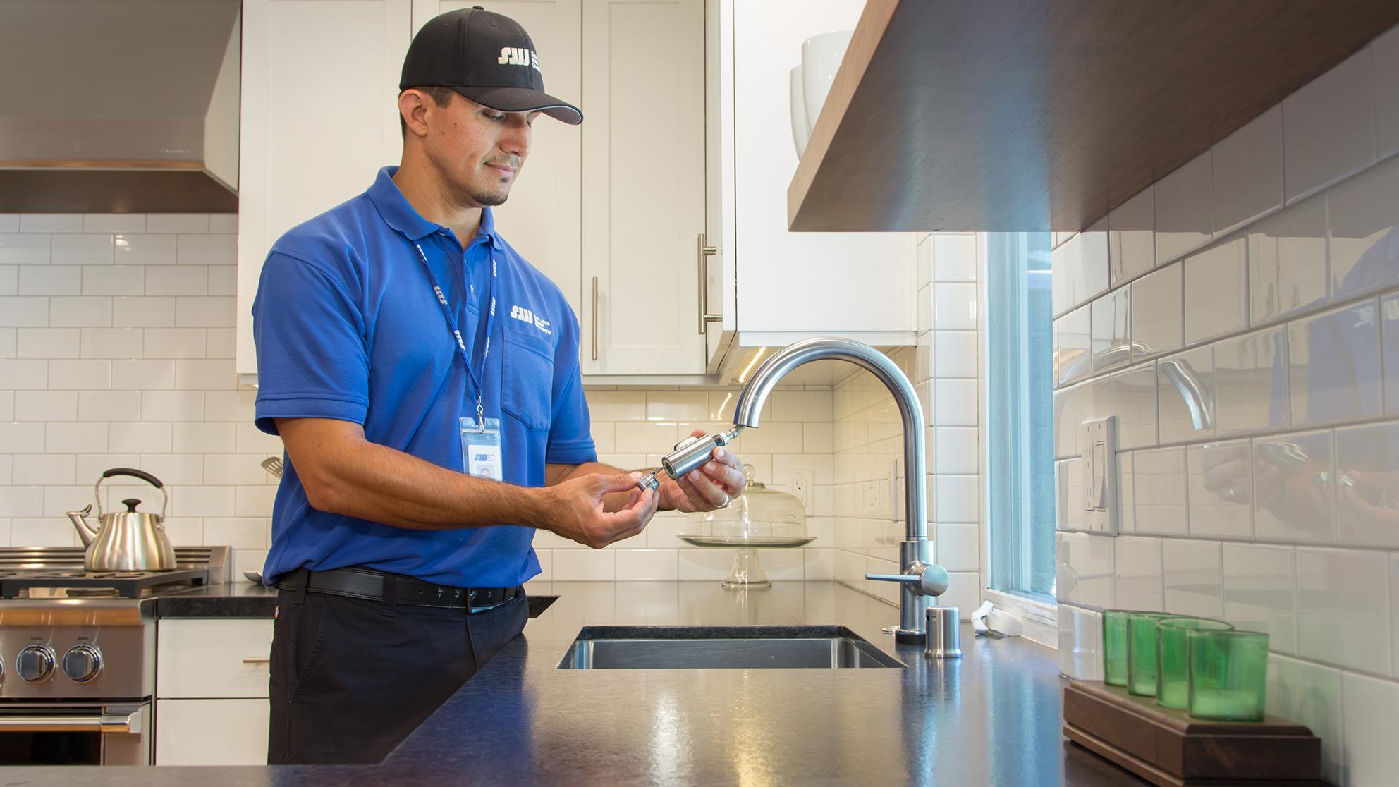 San Jose Water worker examines kitchen faucet