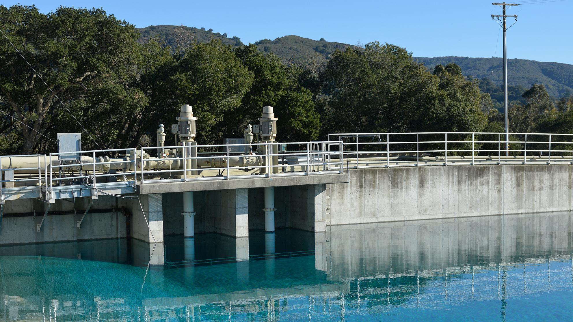 Water reservoir with green hills and blue sky in the background