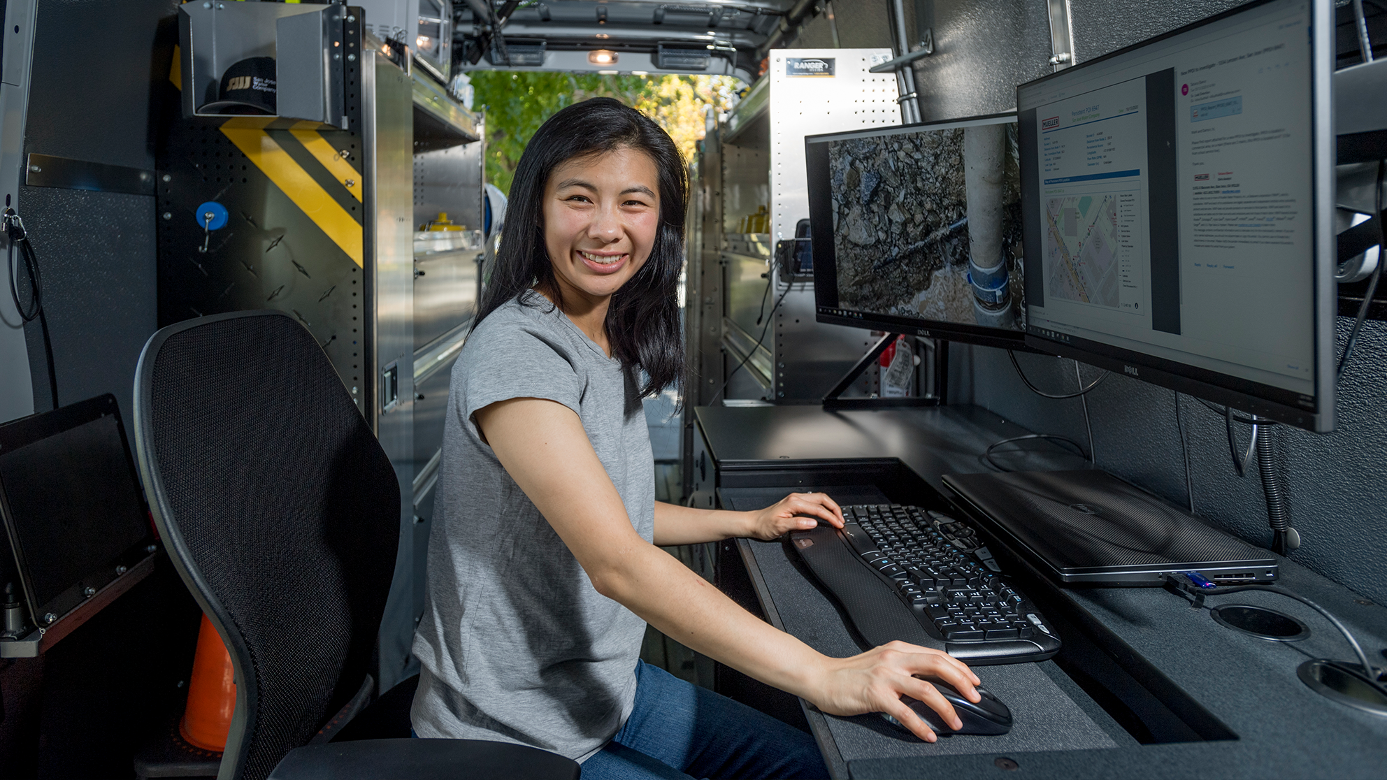 San Jose Water employee in front of monitors and smiling at the camera