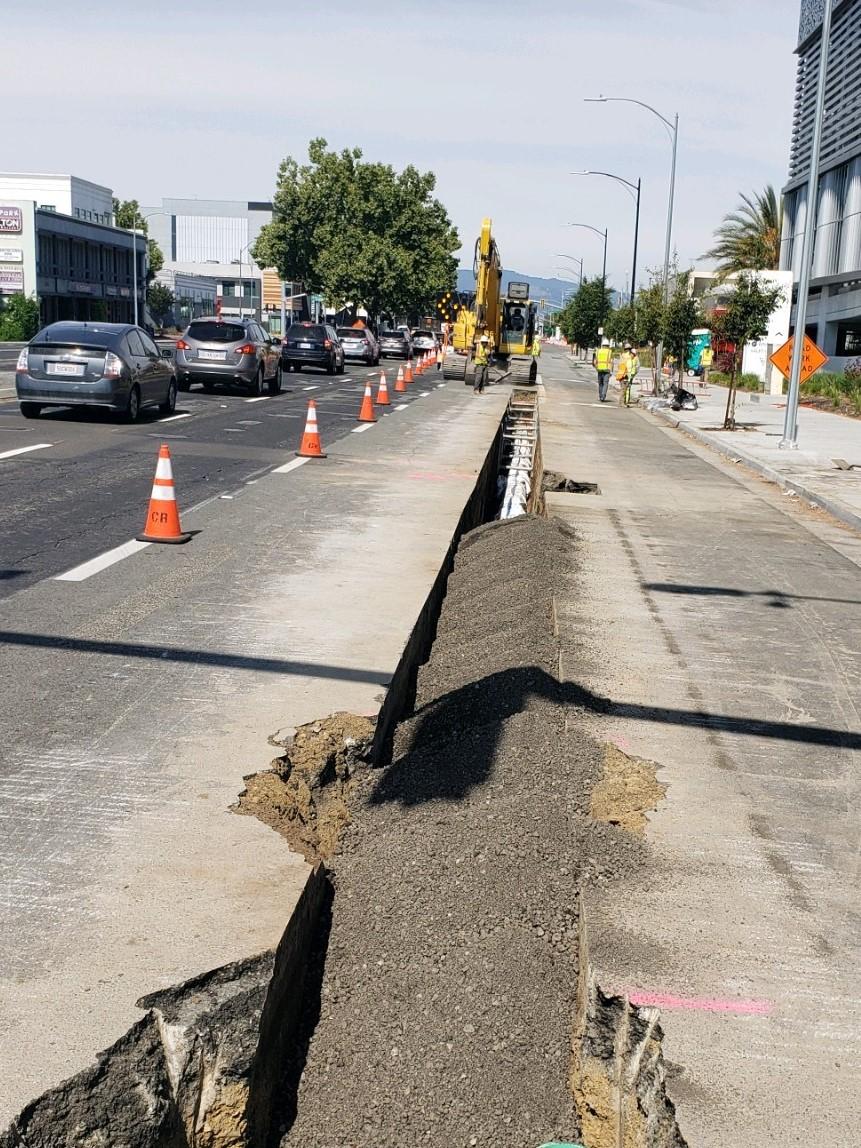 Trench with water main and gravel in street view.