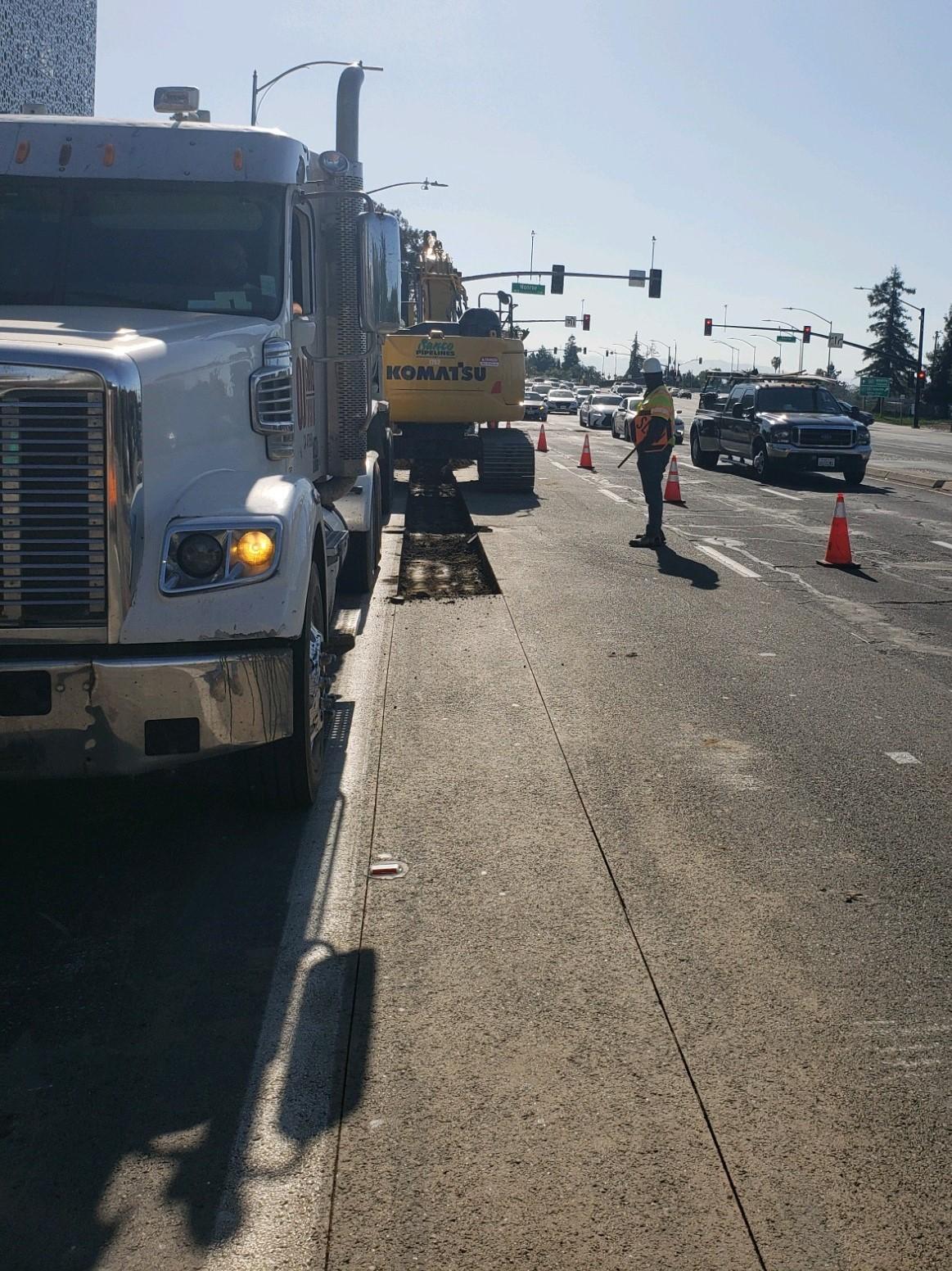 Workers in street within cone zone with traffic flowing