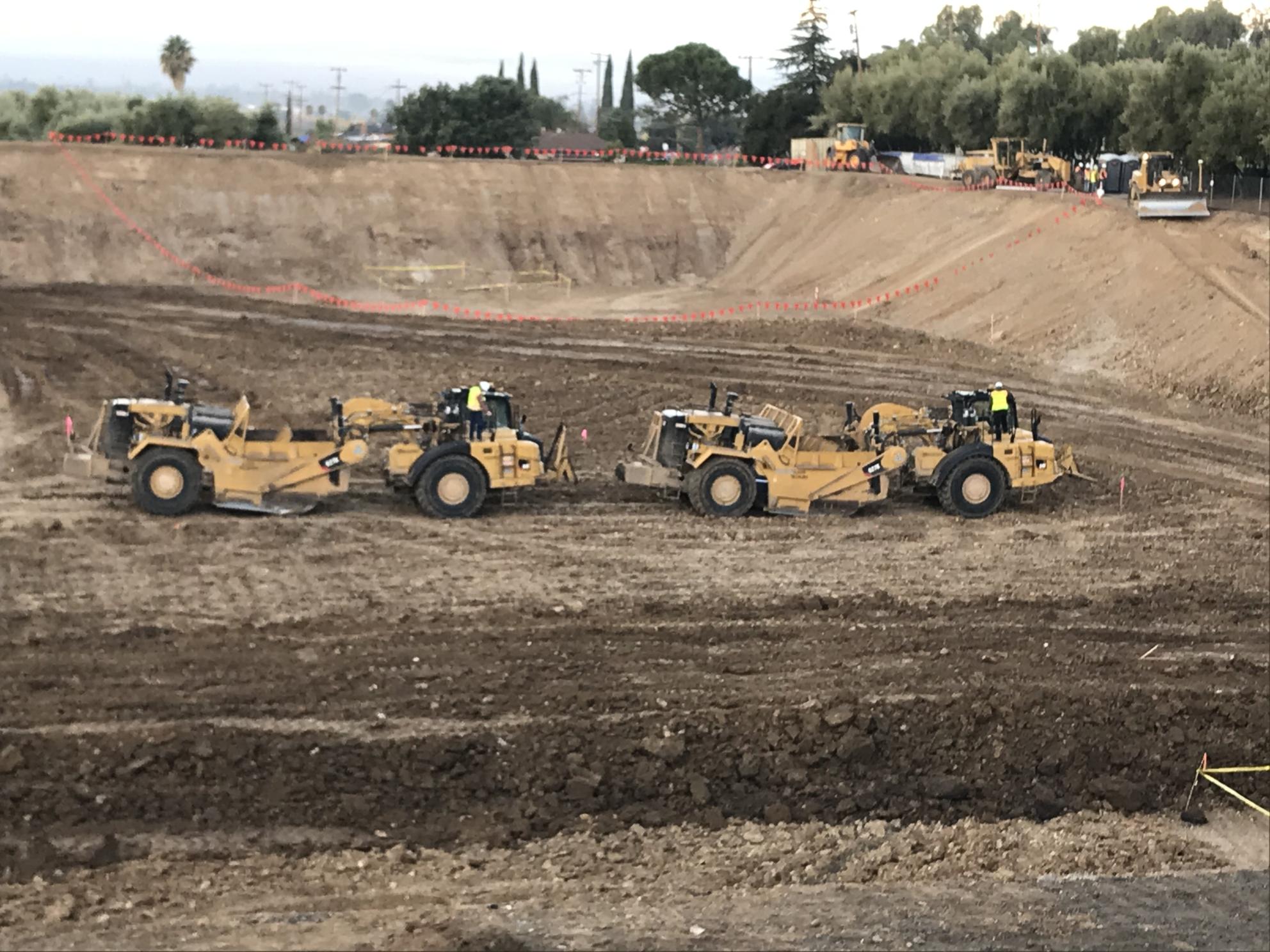 two pieces of heavy machinery in large hole