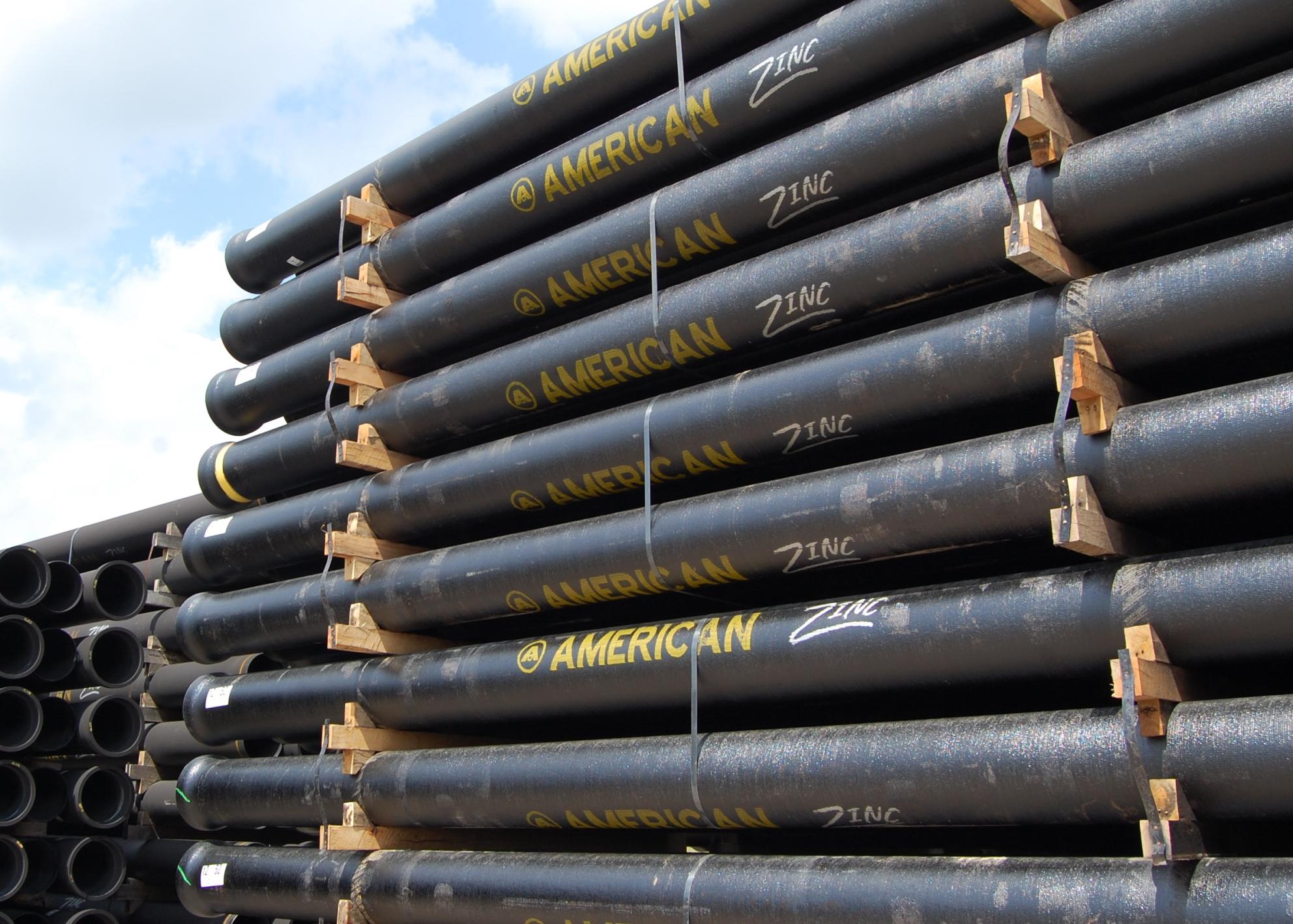 Stack of new zinc coated pipes with sky in the background